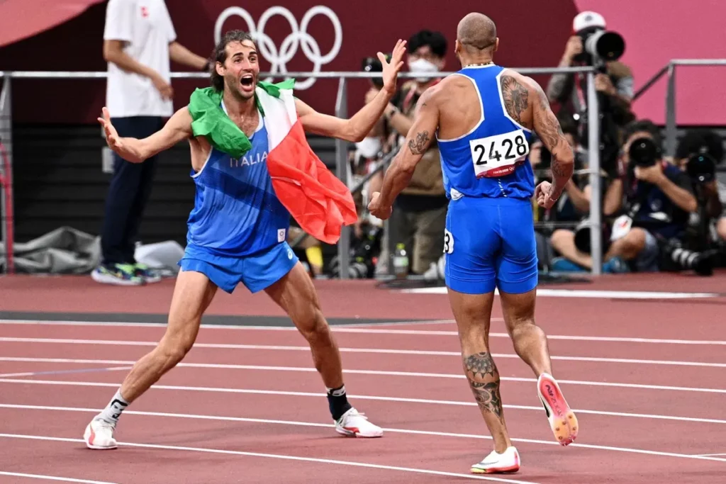 O italiano Gianmarco Tamberi comemora com o saltador em altura Lamont Marcell Jacobs após vencer a final masculina dos 100m nos Jogos Olímpicos de Tóquio 2020 | Foto: AFP